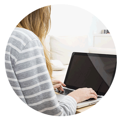 Mujer utilizando una laptop en casa con un suéter de rayas grises y blancas